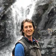 a person smiling in front of a waterfall