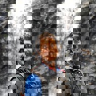 a person smiling in front of a waterfall