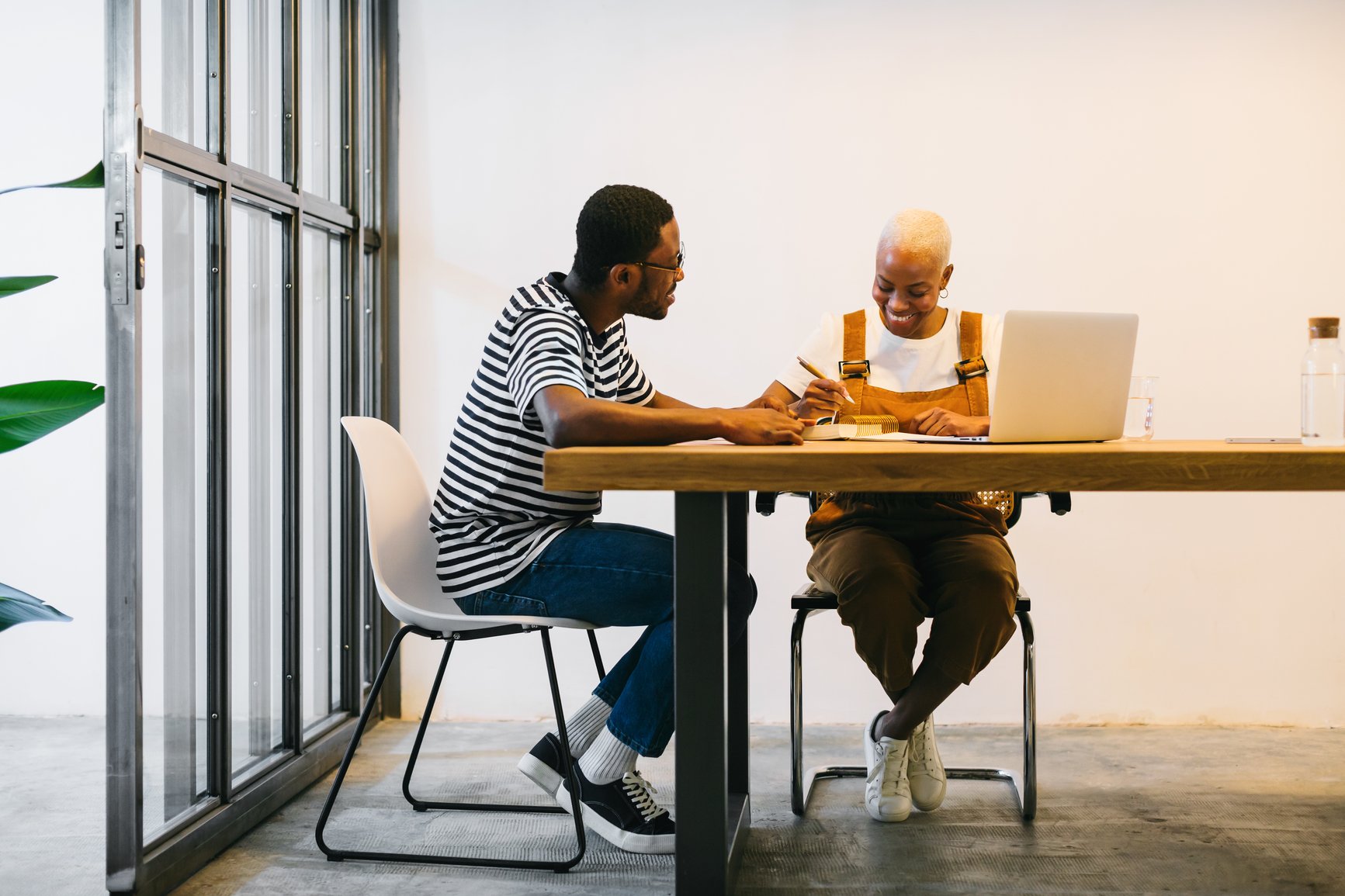 a couple of men sitting at a table looking at a laptop