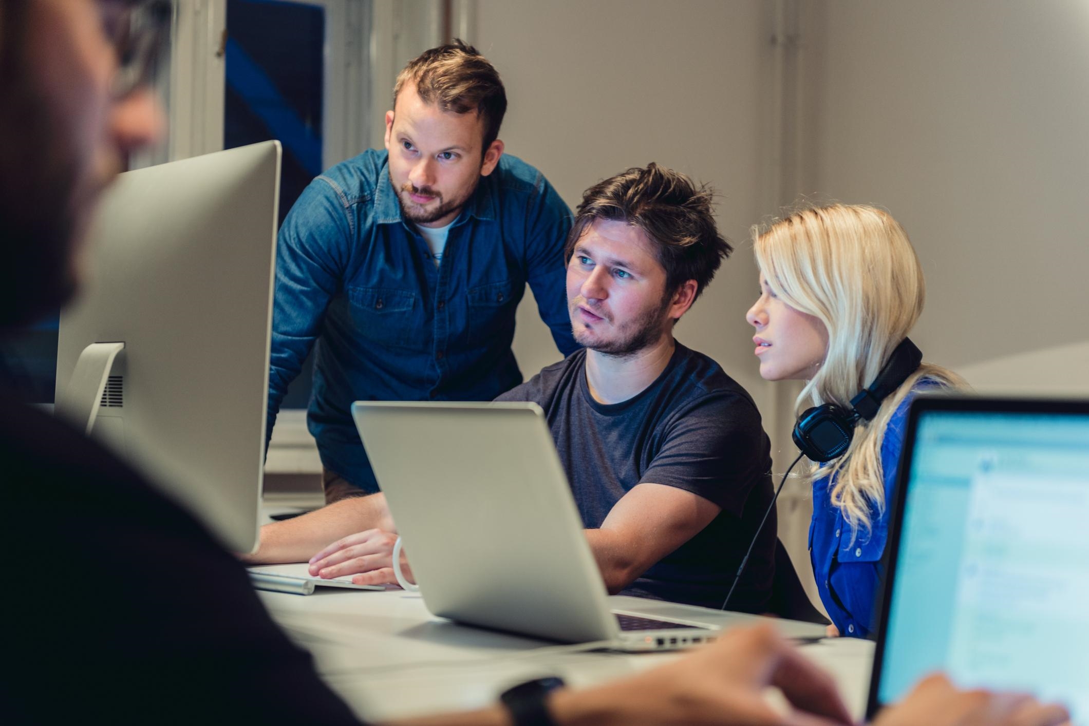 a group of people sitting at a table with laptops