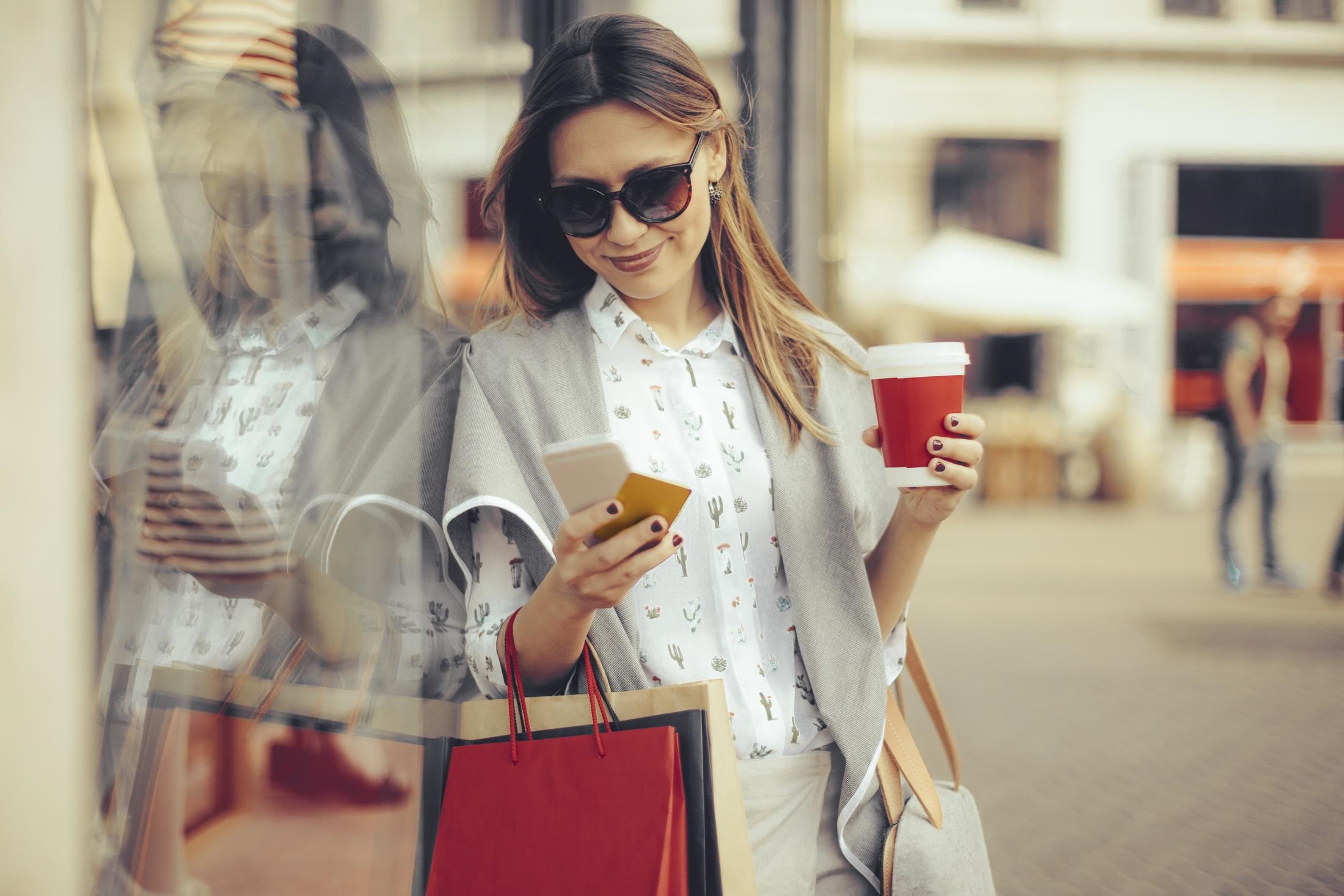 a woman holding a cup and a cell phone